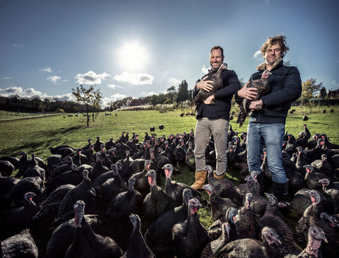 Twee broers in een weiland met allemaal kalkoenen om zich heen