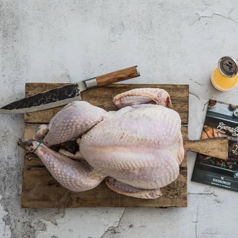 Rauwe kalkoen op een houten snijplank met een vlees mes.